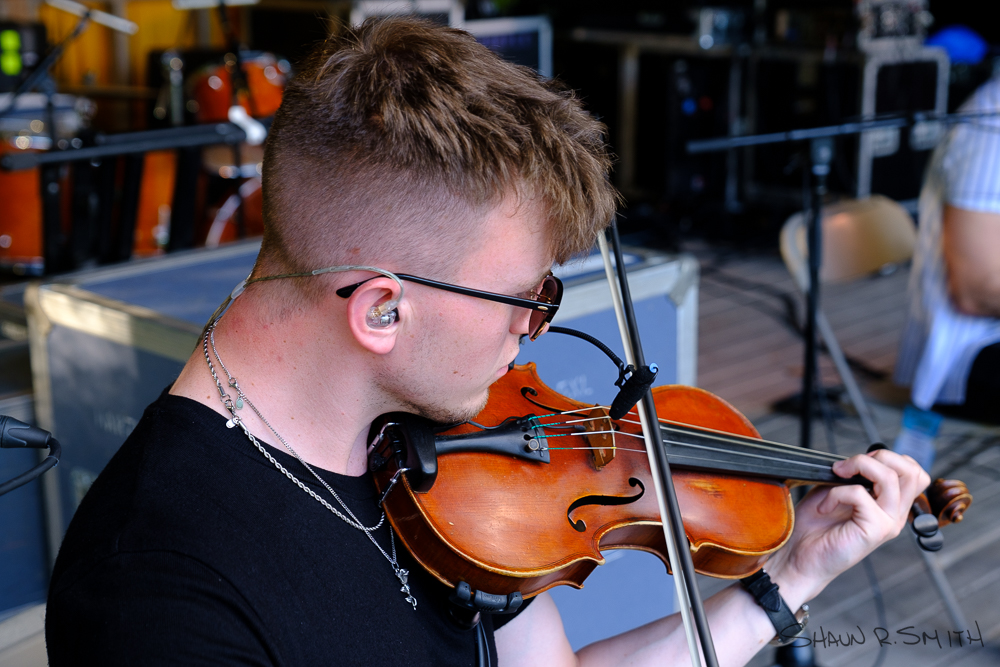 Benedict Morris, fiddle player for Talisk, warms up during soundcheck Thursday, Aug. 18, 2022 on the Camp Stage during the 60th annual Philadelphia Folk Festival (Shaun R. Smith/ The High Note).