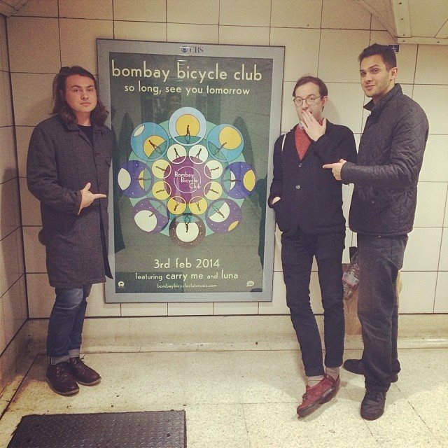 The members of Bombay Bicycle Club with a poster announcing the release of "So Long, See You Tomorrow." (Courtesy of the artist.)